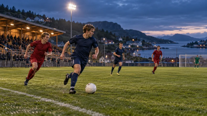 Fotballspillere i røde og mørkeblå drakter på en flomlyst kystbane om kvelden.